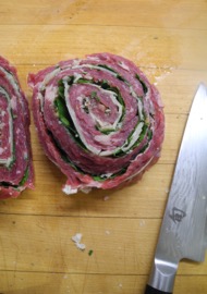 A pinwheel steak stuffed with parsley and Parmesan, ready to be cooked.